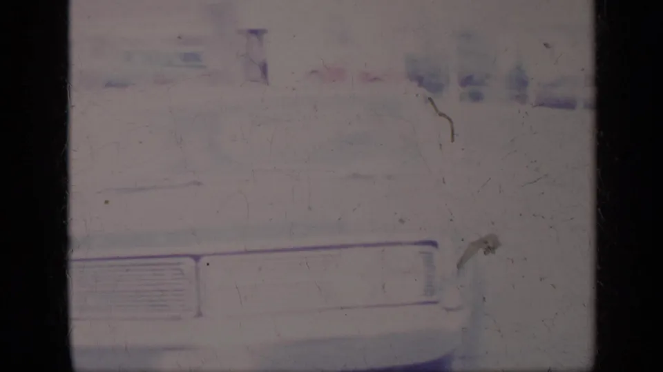 1969 California 8mm frame showing a soft, faded view of a white car front with grille, headlight area and visible film wear.