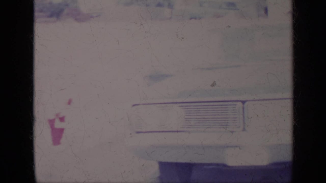 White car front with grille at right and a small pink shape near the center of the frame.