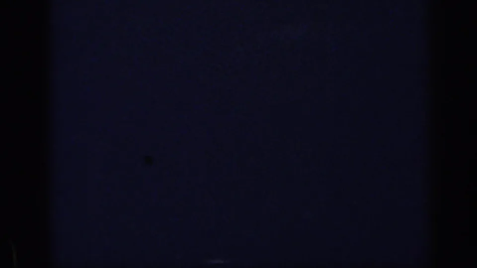 1969 California 8mm frame with heavy dark exposure and a partial view of a man and woman seated at a dining table.