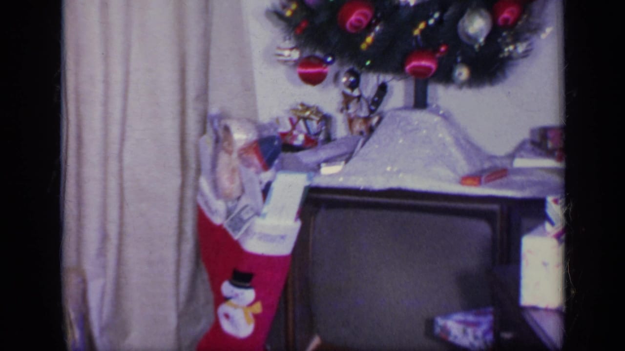 Christmas tree, red stocking, vintage television, and wrapped presents in a living room.