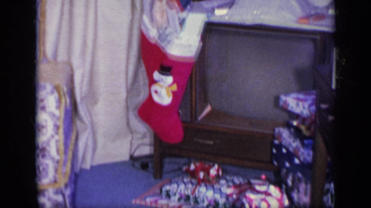 Red stocking beside a vintage television with wrapped presents on the floor.