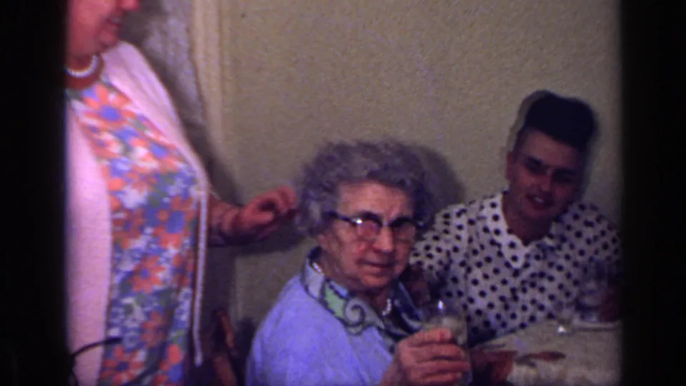 1969 California domestic scene with an older woman seated by a table while another woman stands close beside her.