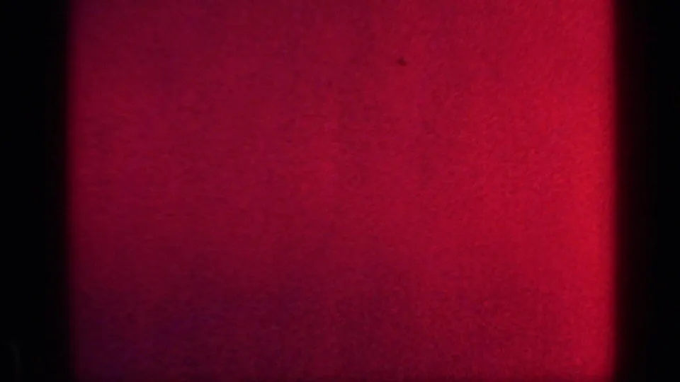 A red-tinted end frame from the 8mm scan shows mostly film texture and light variation, with no clear person or room detail visible.