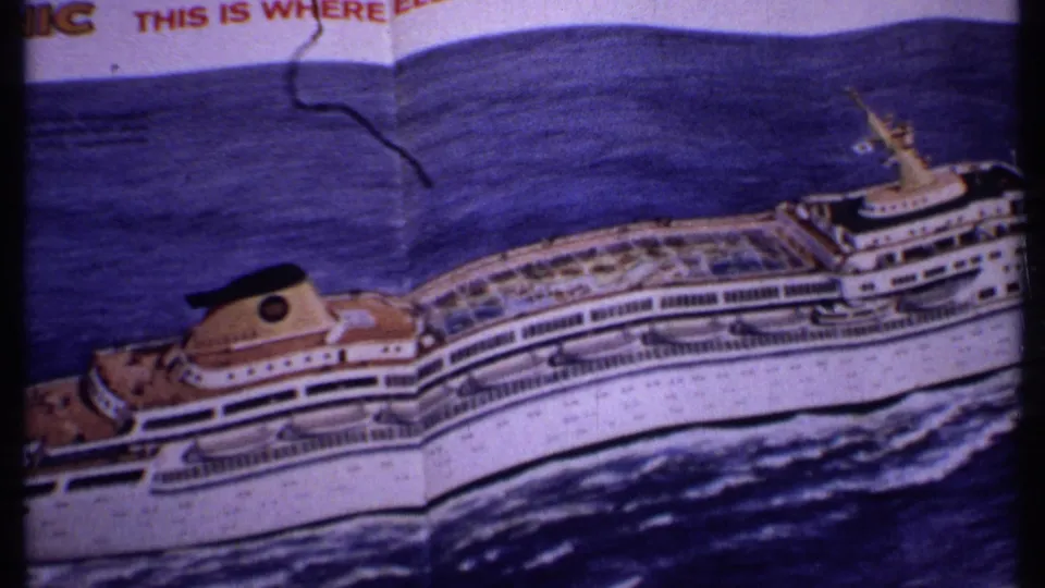 1969 Bahamas frame showing a printed cruise-ship illustration on a folded travel advertisement page, filmed in close handheld view.