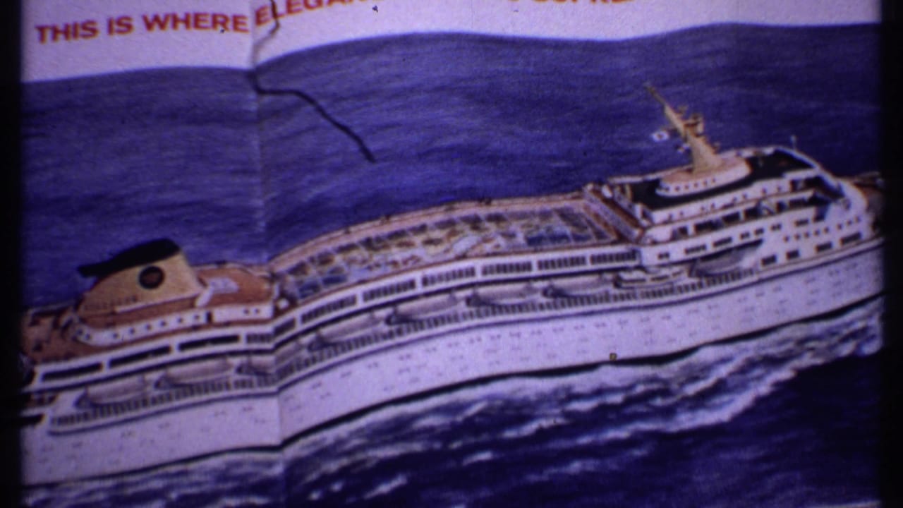 1969 Bahamas home-movie frame showing a printed cruise ship illustration with blue sea artwork and partial red promotional headline text.