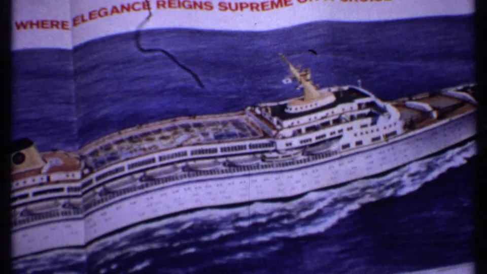 A Bahamas 1969 8mm frame records a printed cruise liner illustration, partial slogan text, blue ocean artwork, and visible film wear.