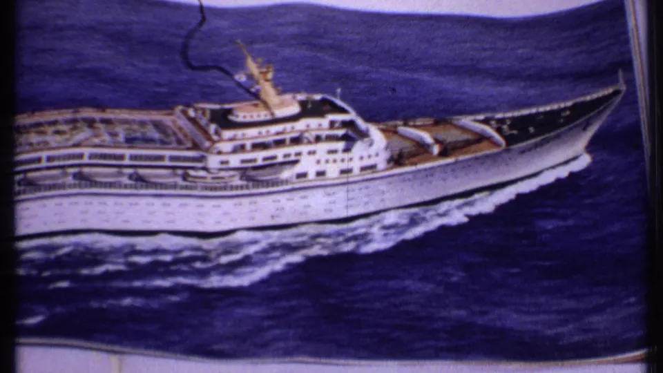 1969 Bahamas home-movie view of the lower-left printed ship photo, with the cruise vessel, ocean wake, paper edge, and film grain visible.