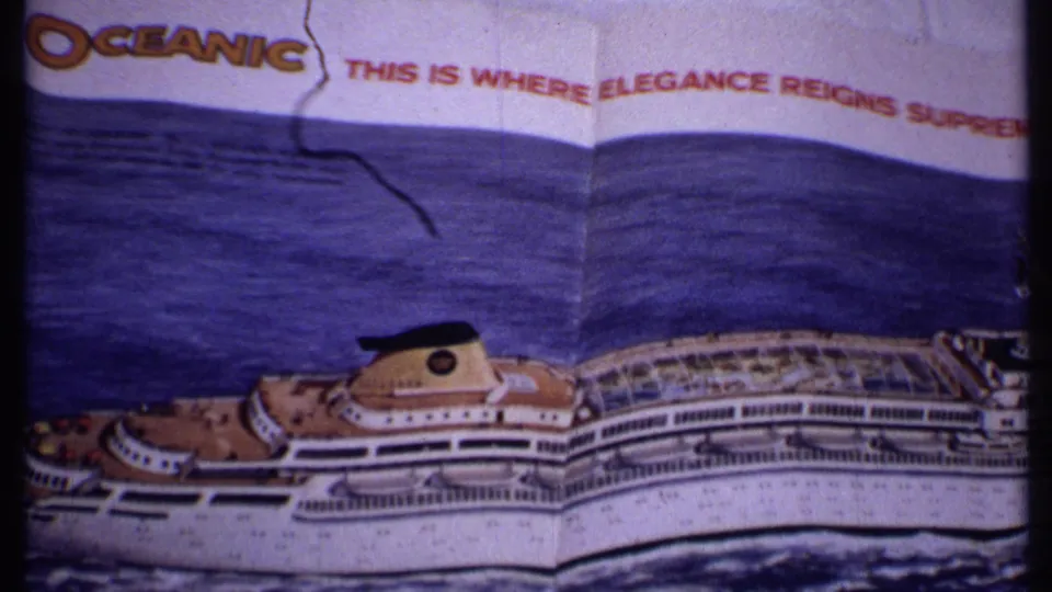 Frame from the 1969 Bahamas clip showing partial OCEANIC lettering, red headline text, and a printed white cruise ship on dark blue sea.