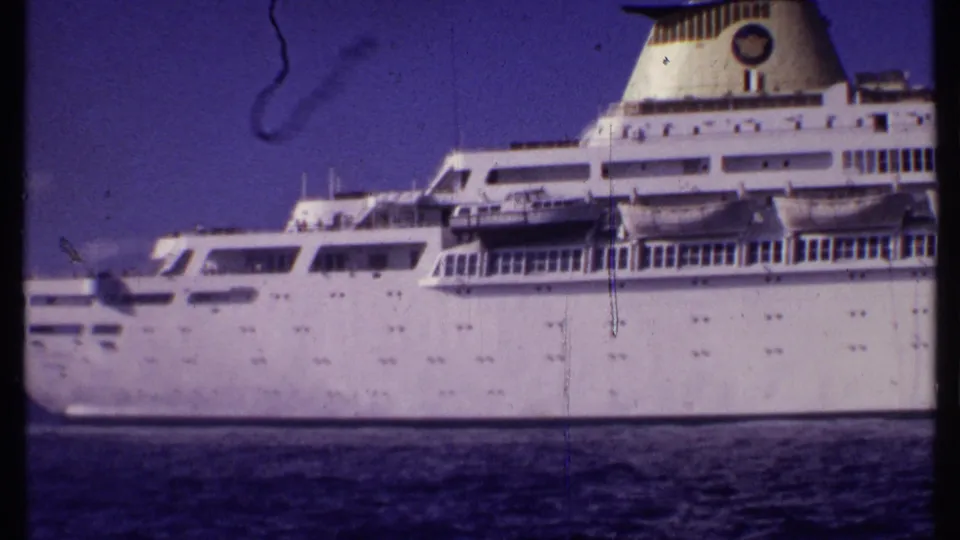 1969 Bahamas 8mm footage shows the white Oceanic cruise ship in side profile with rows of windows, decks, and funnel above dark water.