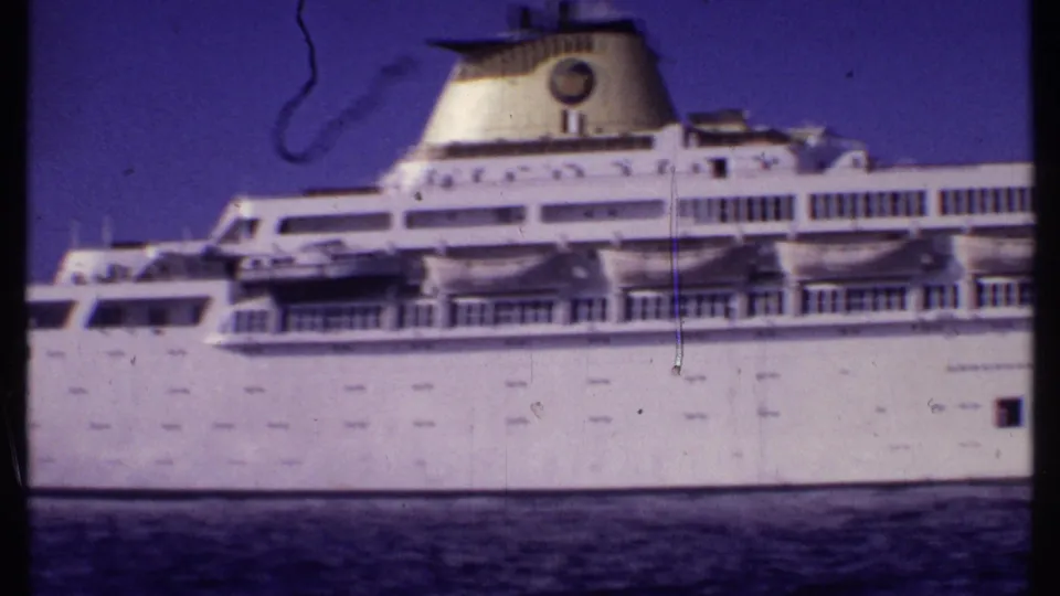 The Oceanic cruise ship remains in side view, with its white hull, upper decks, funnel, blue sky, and dark water softened by 8mm film texture.