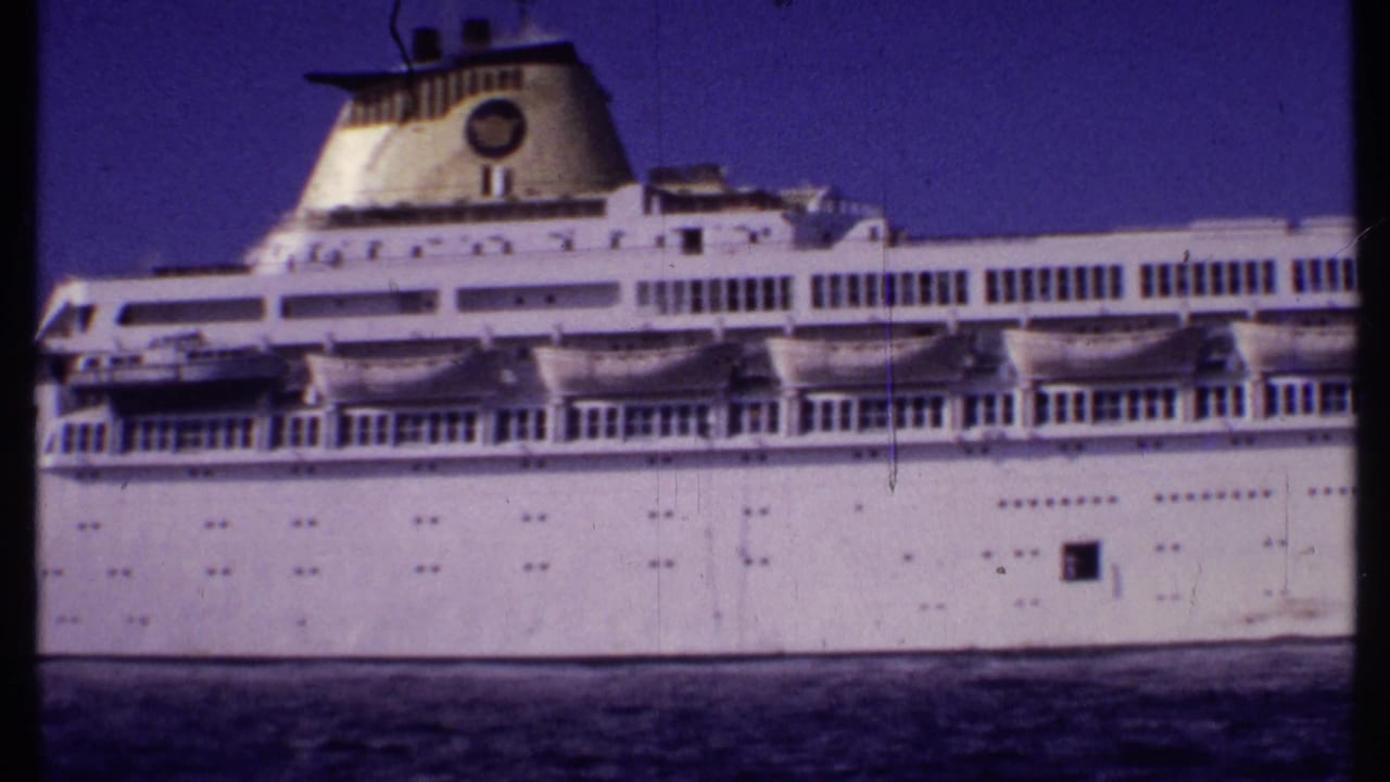 Large white passenger ship seen broadside on dark water under a blue sky.