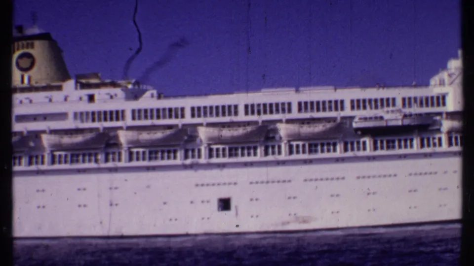 1969 Bahamas frame of a white cruise ship or passenger vessel seen from the side, with a funnel, lifeboats, and rows of windows.