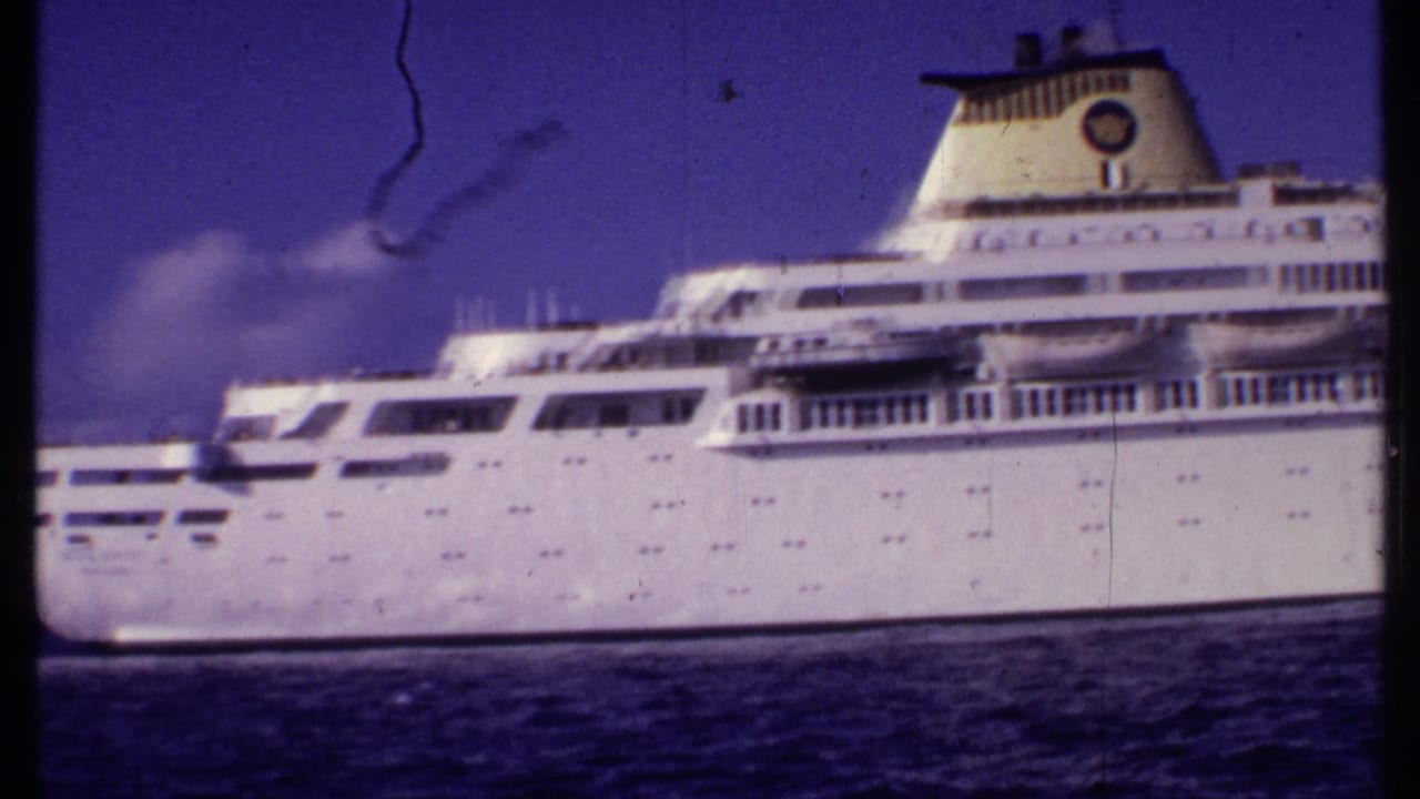 1969 Bahamas 8mm frame showing the bow and midsection of a large white cruise ship from a nearby vessel.