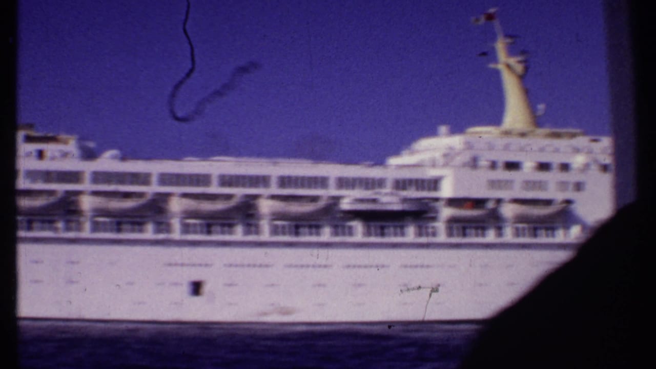 1969 Bahamas 8mm frame showing the cruise ship's midsection with lifeboats, railings, and a dark frame edge in view.