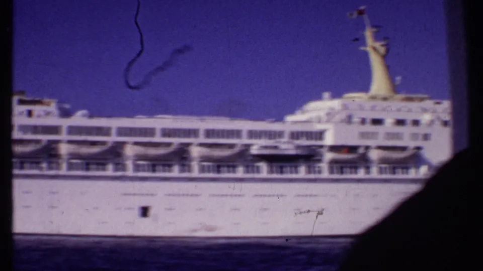1969 Bahamas 8mm frame showing the cruise ship's midsection with lifeboats, railings, and a dark frame edge in view.