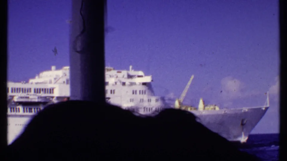 1969 Bahamas 8mm frame showing the bow and upper decks of a white cruise ship seen from another vessel.