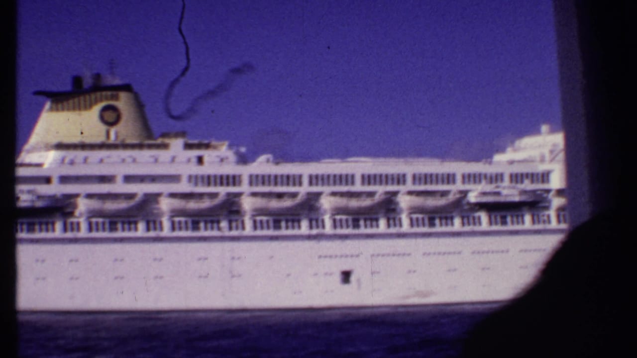 Close 8mm view of the cruise ship's side, showing deck rows and funnel in the metadata-supported Bahamas setting.