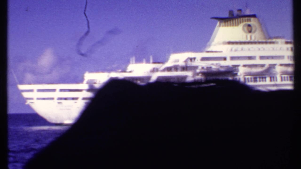 1969 Bahamas frame showing the aft portion of a white cruise ship passing beyond a dark passenger silhouette.