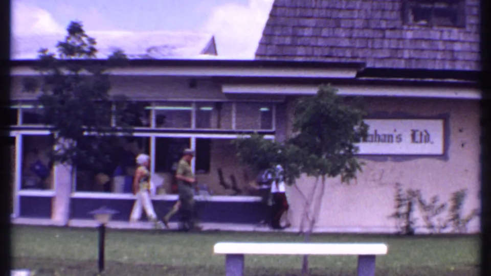 1969 Bahamas frame with pedestrians moving along the sidewalk outside the Kahan's Ltd. storefront.