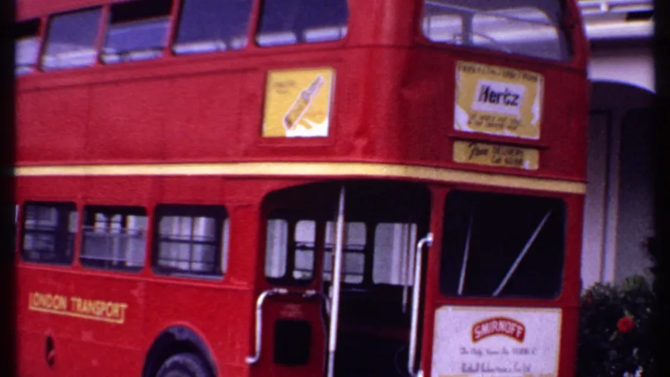 Close 1969 Bahamas 8mm view of the red London Transport double-decker bus, with open entry doors and upper advertising panels.