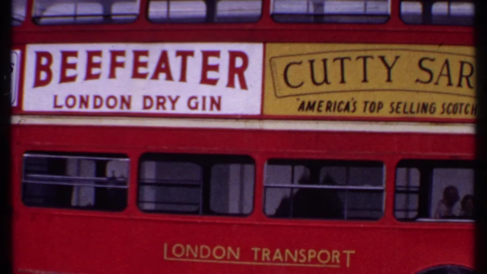 1969 Bahamas frame with a red double-decker bus, visible passengers, and large Beefeater and Cutty Sark advertising panels.
