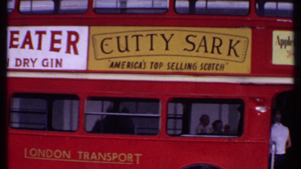 1969 Bahamas home-movie still showing the bus side with Cutty Sark and Appleton Rum advertisements and passengers behind the windows.