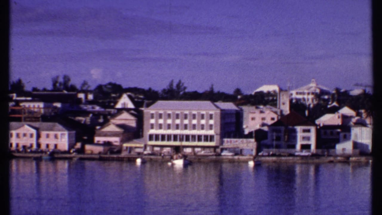 Harborfront buildings with a larger pale block-like structure near the water.