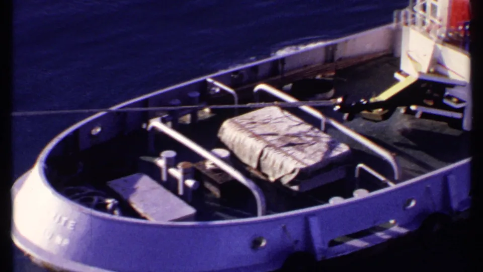 White vessel deck with railings, covered cargo, and blue water visible in a 1969 Bahamas home-movie frame.