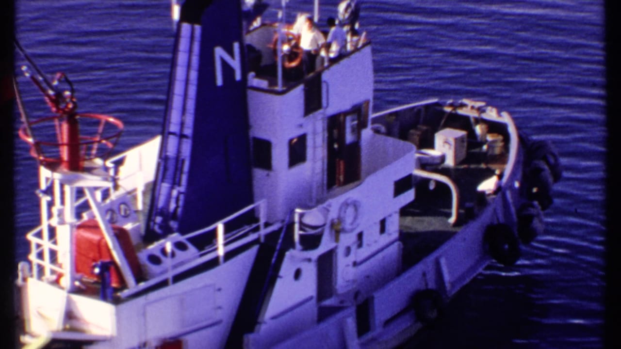 Tugboat stern and cabin viewed from above, with crew visible near the bridge.