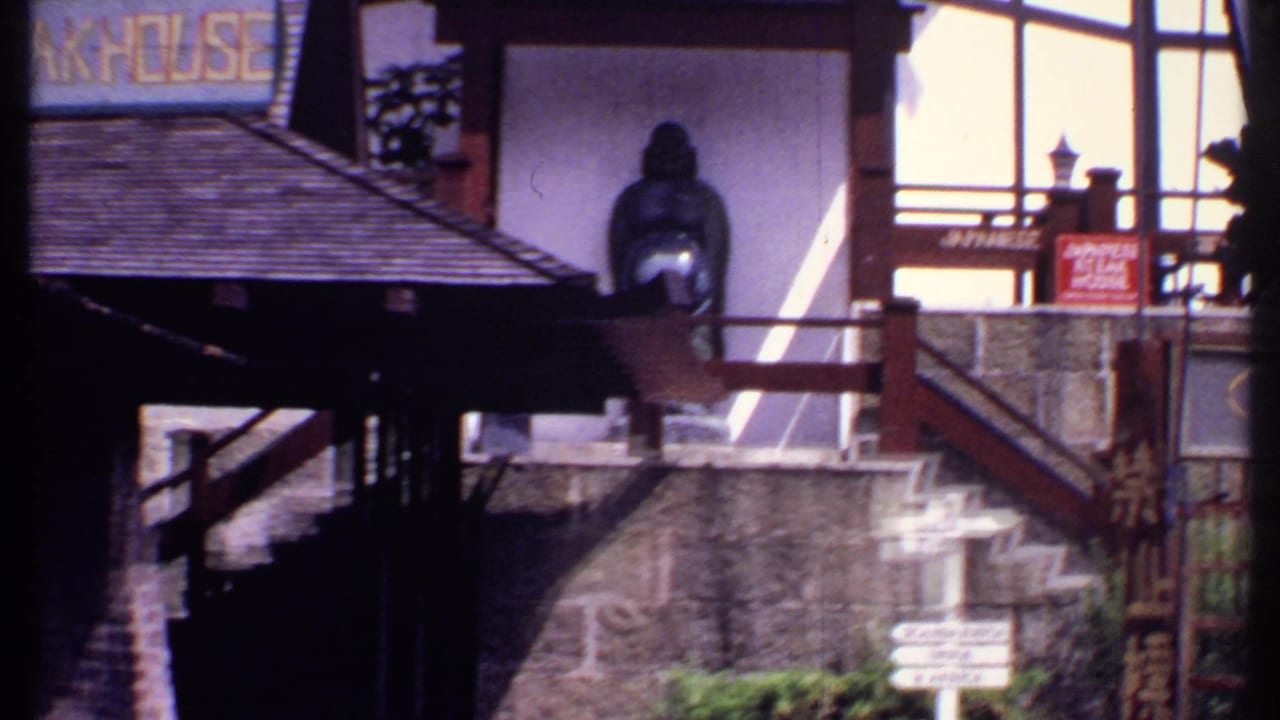 Low-angle view of resort buildings with tiled roofs, a statue, stone walls, stairs, and a partial Kings Inn sign.
