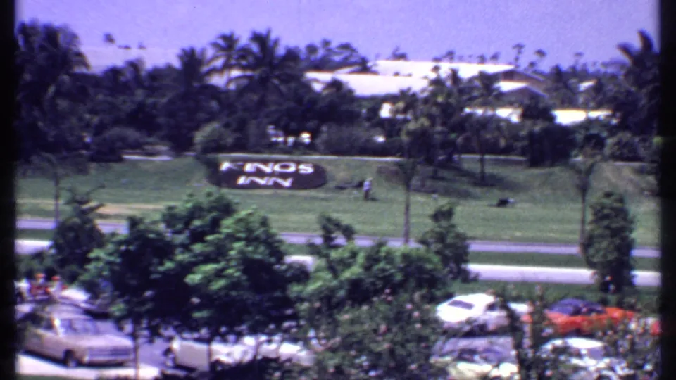 1969 Bahamas resort view with a Kings Inn sign on a grassy slope, classic cars in front, palms, and low hotel buildings.
