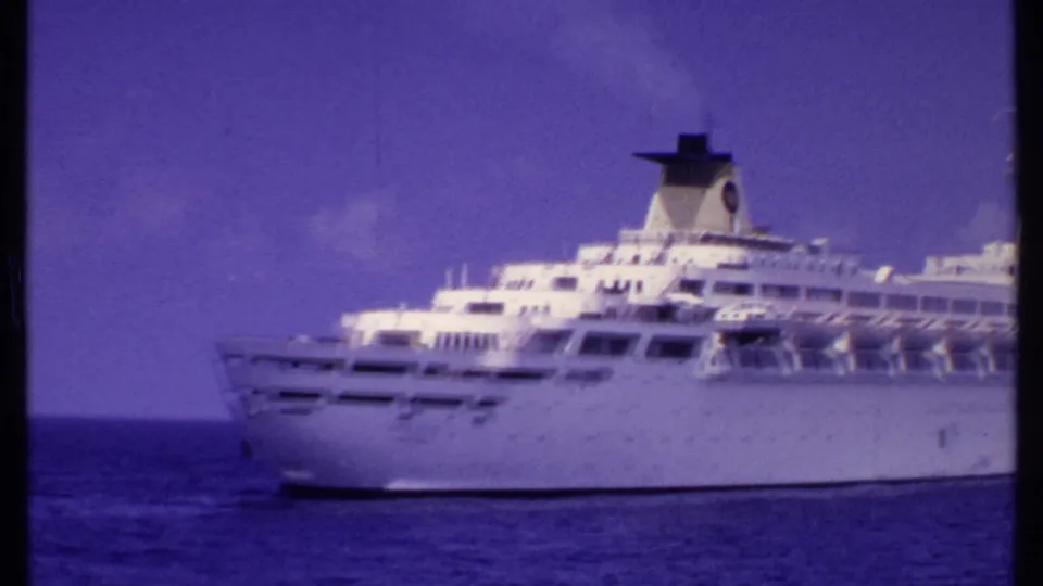 Large white cruise ship seen on open water in the Bahamas, framed in soft 1969 8mm home-movie color.