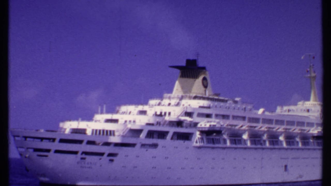 1969 Bahamas-associated 8mm frame showing a large white cruise passenger ship with decks, funnel, and bow visible at sea.
