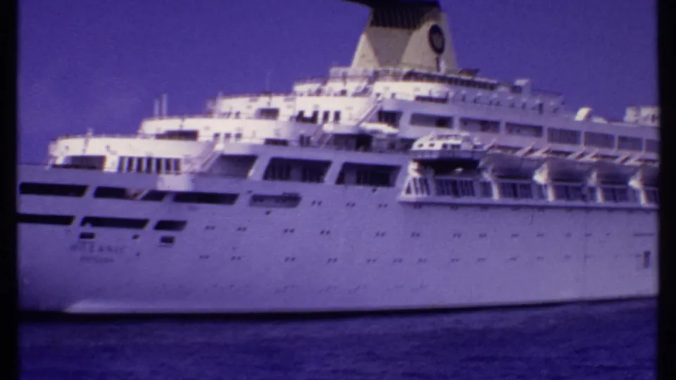 Tight 8mm view of the large white passenger ship, showing hull windows, deck railings, lifeboats, and funnel during a 1969 Bahamas-associated voyage.