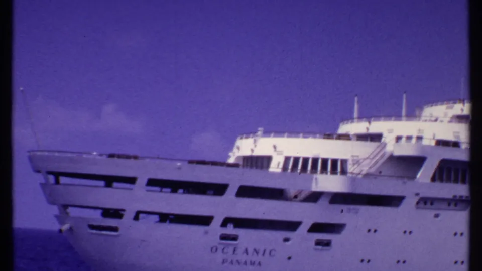 1969 Bahamas 8mm frame showing the white Oceanic Panama cruise ship against open sea with a purple film cast.