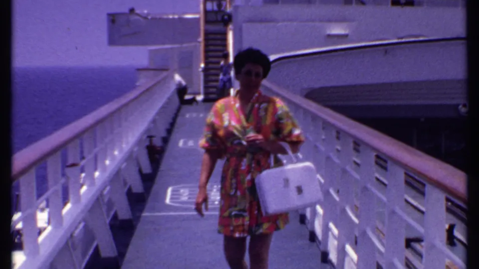 Close view of a woman carrying a white handbag on a cruise ship gangway, with decks, railings, and sea in the background.