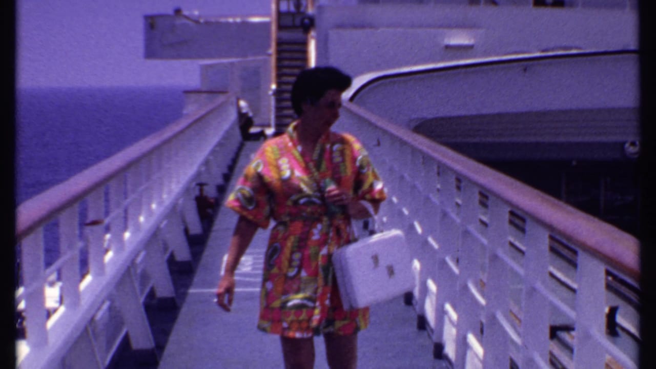 Woman in a colorful dress walking along a cruise ship deck with ocean behind her.