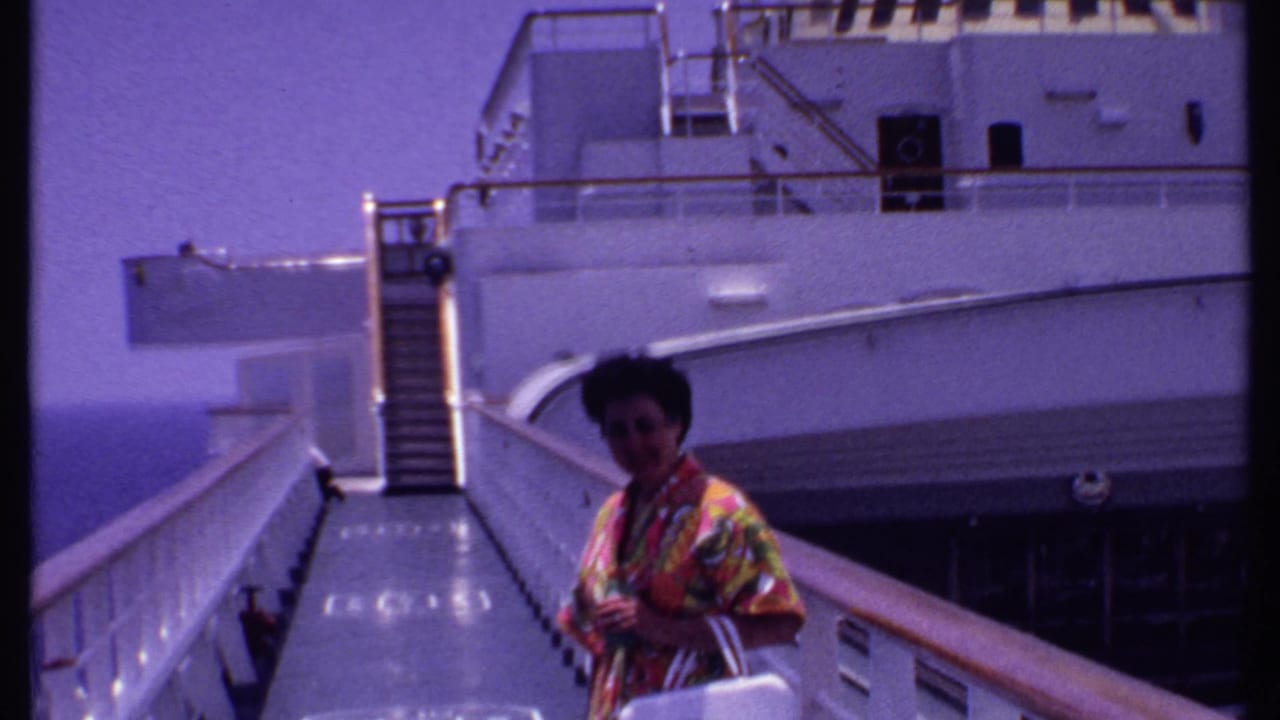 1969 Bahamas cruise home-movie frame showing a woman on a gangway with a white ship exterior and ocean visible behind her.