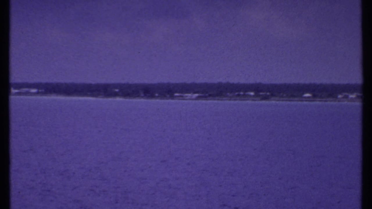 Calm water with a distant low shoreline under a hazy sky.