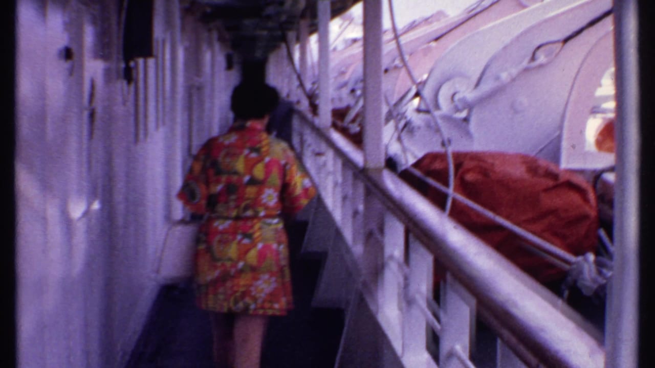 Woman in a colorful patterned dress walking along a cruise ship deck beside white railings.