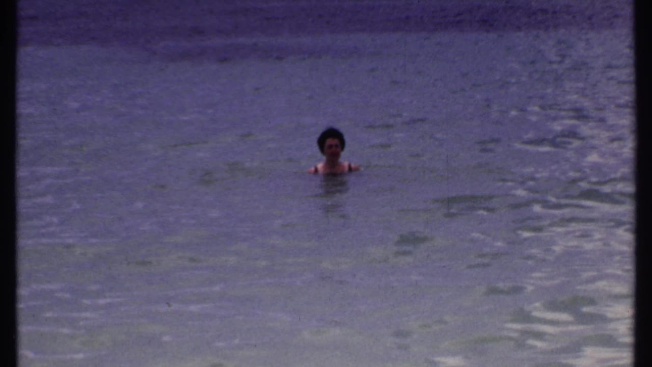 Woman floating in open water with ripples around her shoulders.