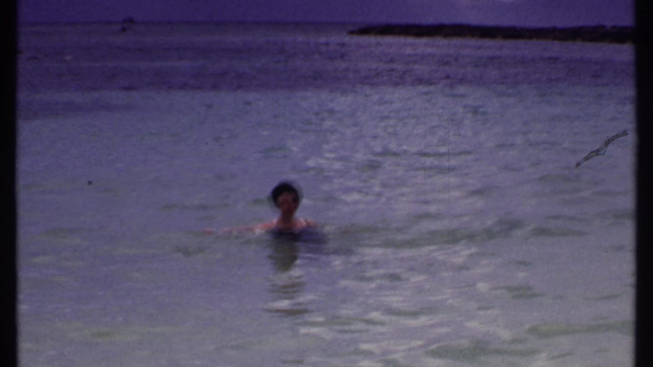 Woman in a dark swimsuit swimming alone in calm Bahamas sea water, from 1969 8mm home-movie footage.