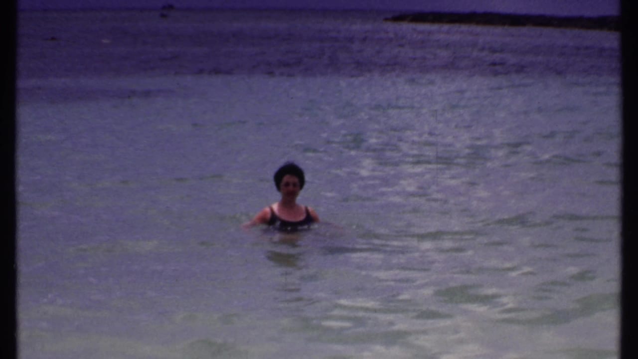 Woman facing the camera while swimming in calm blue water.