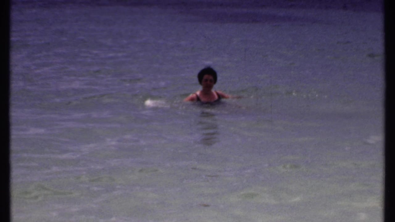 Adult woman swimming in calm water with her head and shoulders visible.