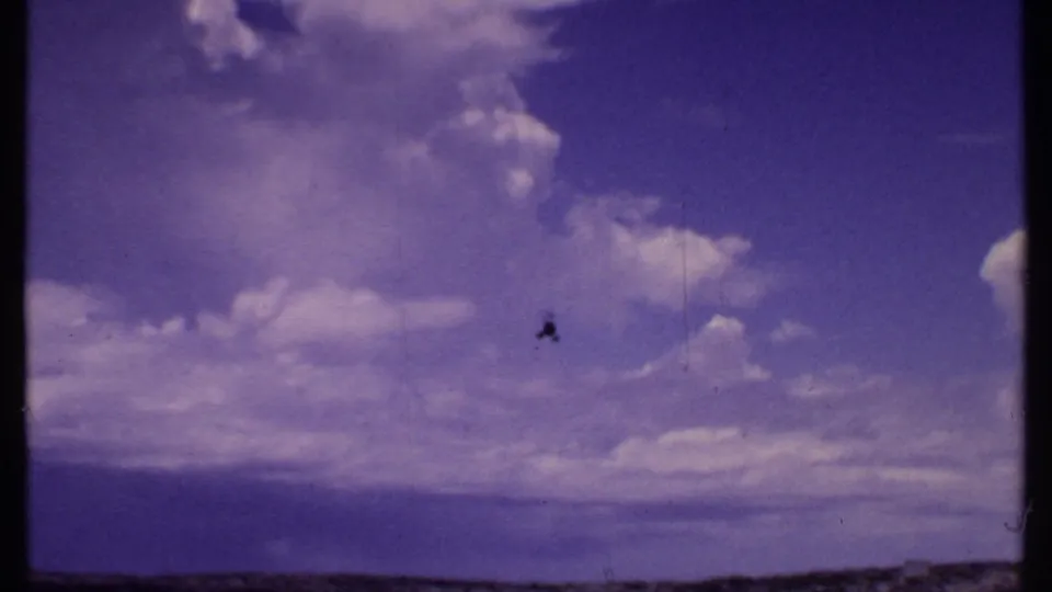 1969 Bahamas 8mm view of a helicopter overhead with clouds and a low coastal horizon below.
