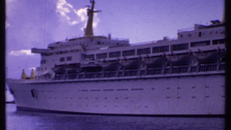 1969 Bahamas harbor view of a white multi-deck cruise ship with lifeboats, railings, mast, and waterline visible.
