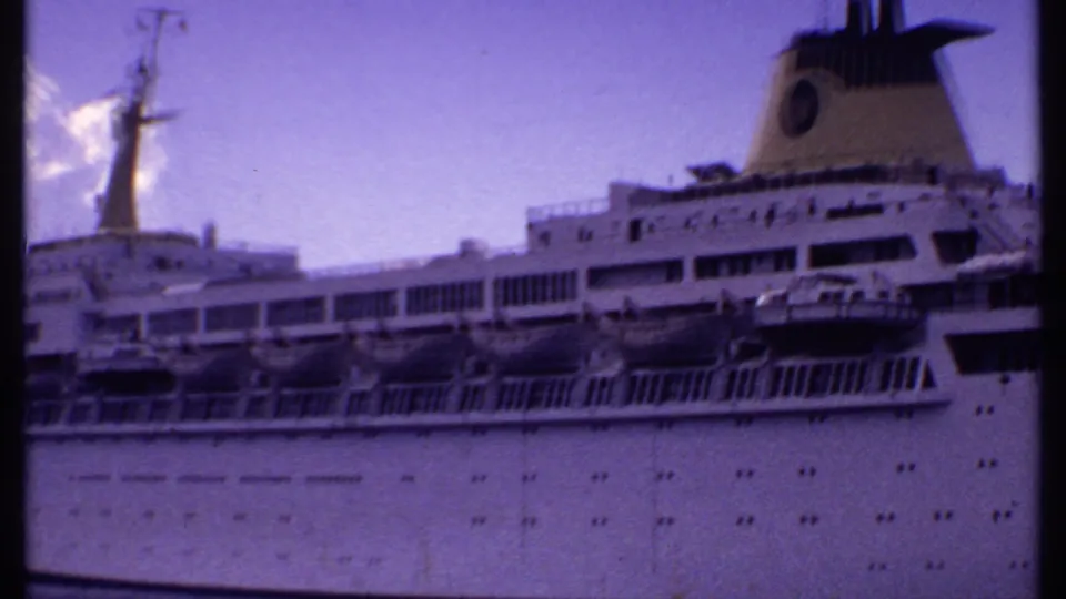 Close 8mm view of the cruise ship side in the Bahamas, with hull portholes, upper decks, funnel, and lifeboats.