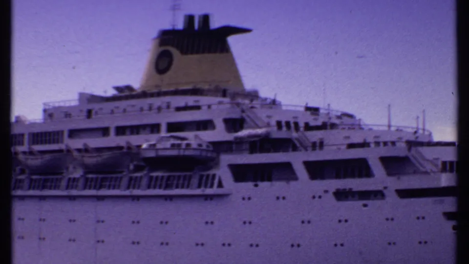 1969 Bahamas view across a docked white cruise ship, showing lifeboats, deck structures, portholes, and funnel detail.