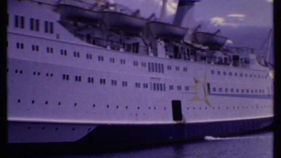 1969 Bahamas frame of a docked cruise ship side, including a yellow sun emblem, portholes, lifeboats, and an open hull doorway.