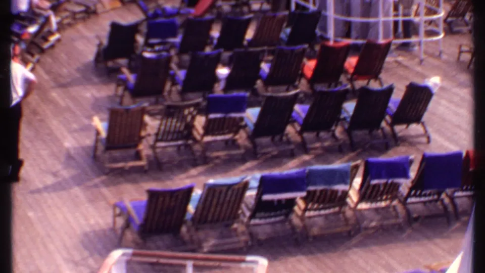 Rows of dark and colorful lounge chairs fill a 1969 Bahamas cruise ship deck, with a few passengers at the edges.